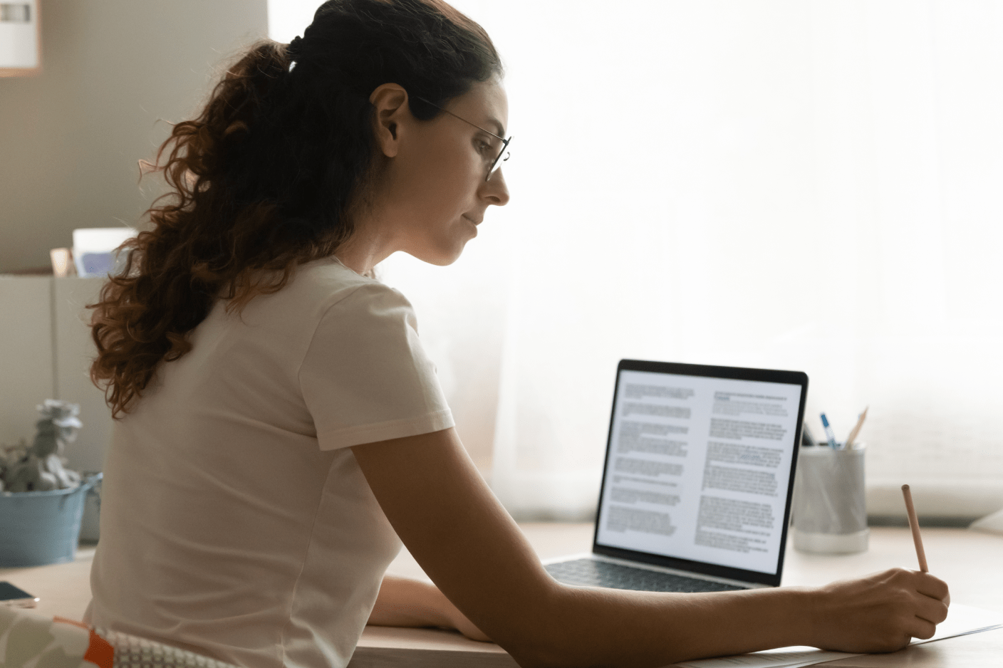 Image of a person with a laptop and a pencil